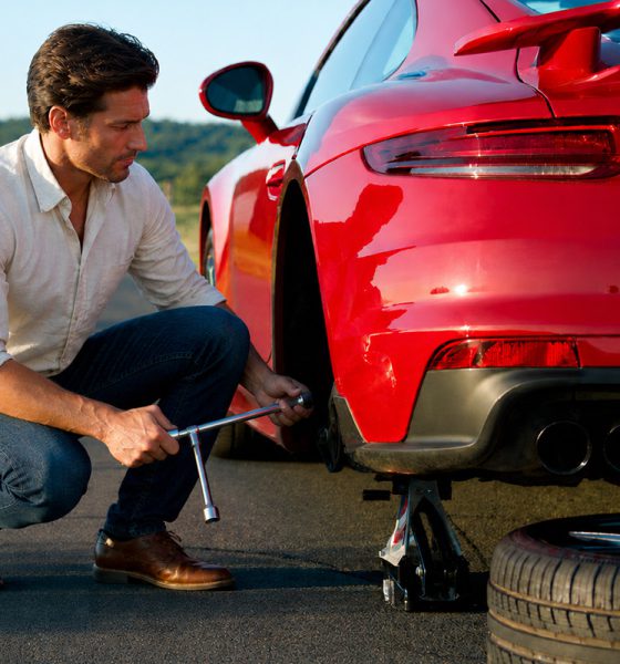Man Changing A Flat Tire On The Side Of The Road