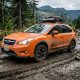 Orange 2015 Subaru Crosstrek driving down a dirty road
